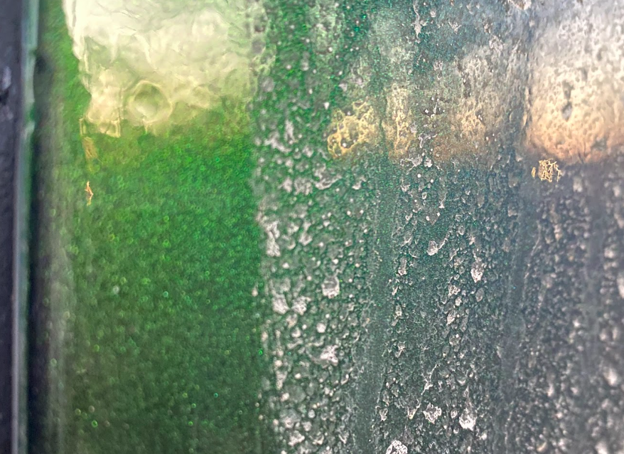 A blurry photo with a greenish surface on the left and a dirty, white-dusted surface on the right side.