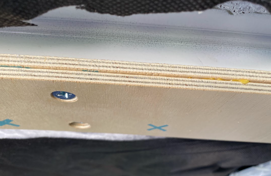 A close-up of two thin strips of plywood, screwed to the ceiling of a van.