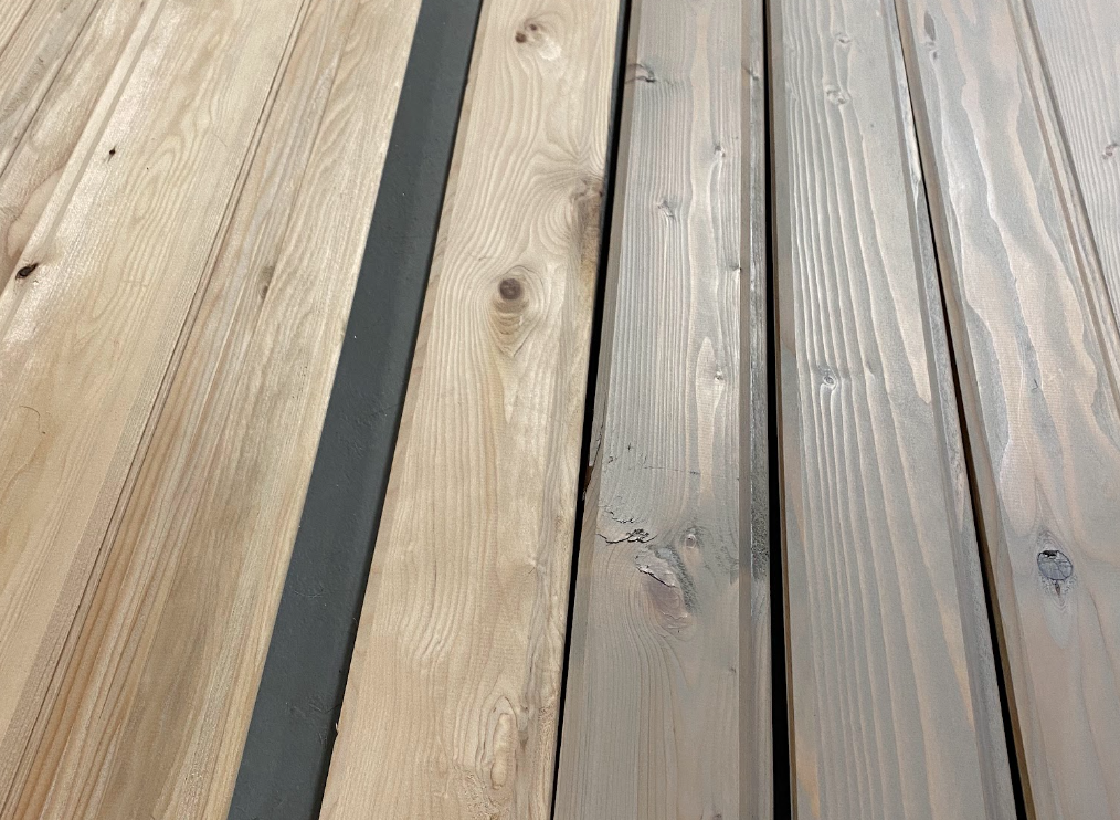 A close up of tongue and groove boards. The ones on the left are plain pine and the ones on the right have a light grayish tint.