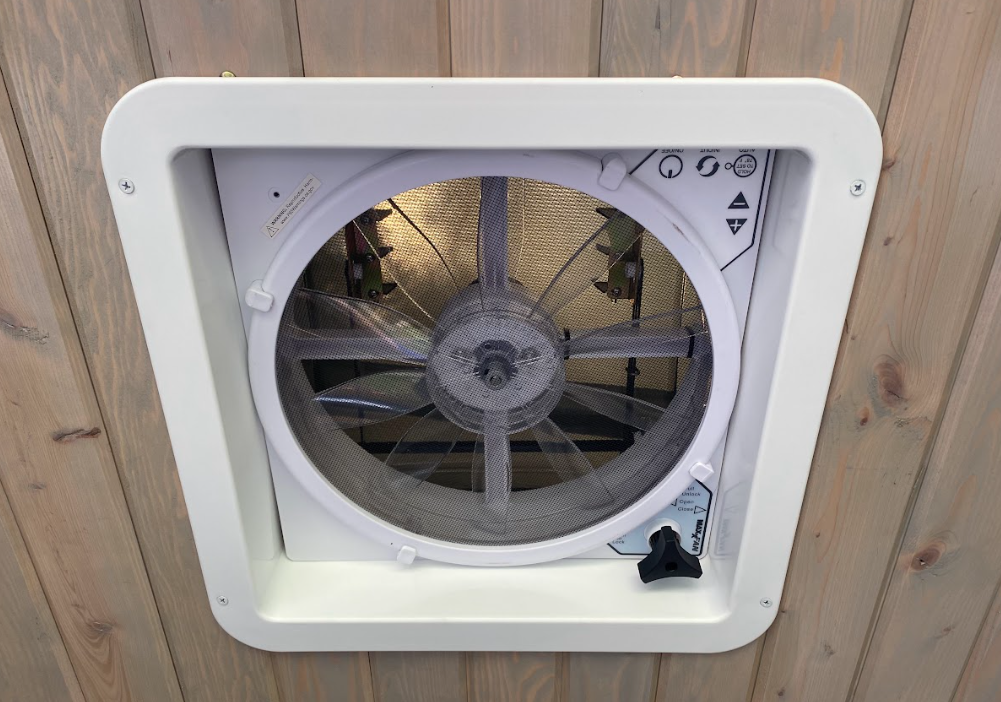 A view toward a wooden ceiling with a square fan installed in it.