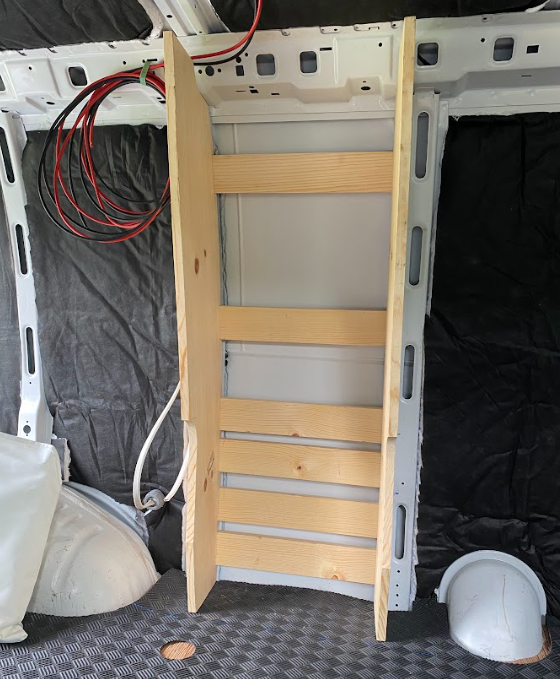 The cabinet frame from the last photo, placed into the interior of a cargo van. The back has six horizontal cross-pieces.