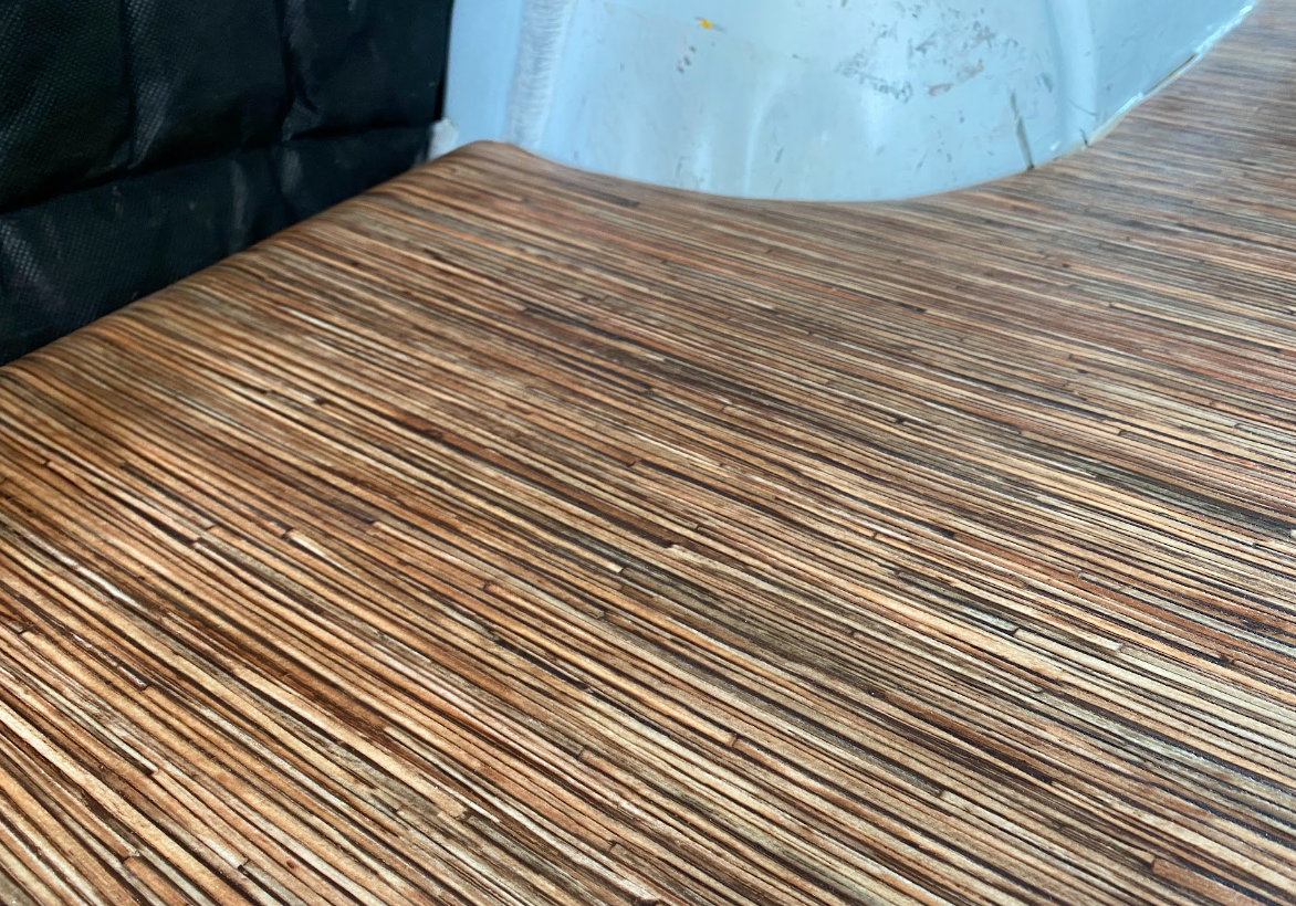 A close up photo of vinyl flooring, which looks like pressed strands of wood.