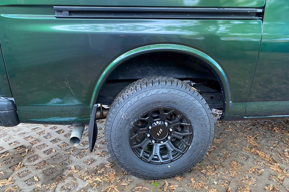 A close up photo of a van tire with a mud flap installed behind it.