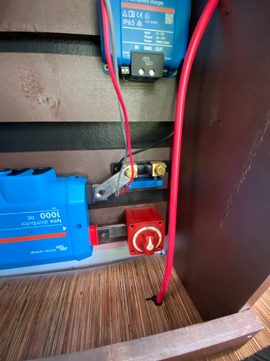 A picture of a cabinet with electrical equipment inside and a wire coming up through the floor of the cabinet.