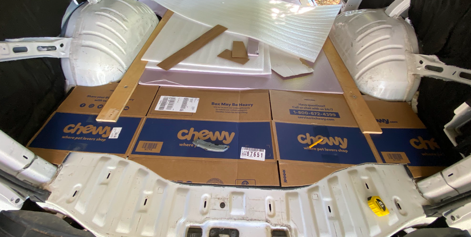 A cardboard Chewy box cut to fit into the rear area of a cargo van.