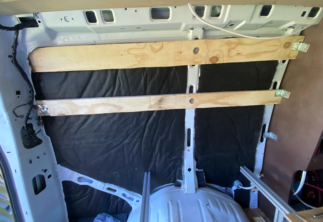 The rear, driver-side area of the van, with two horizontal wall studs installed.