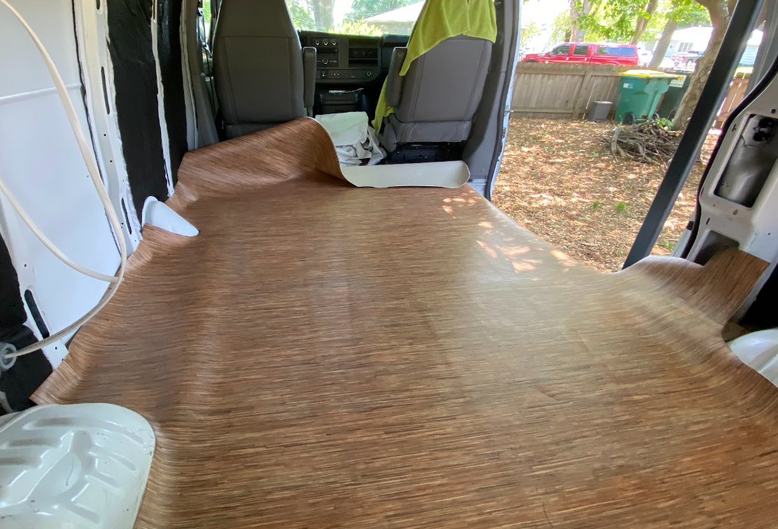 A too-large piece of vinyl flooring in a cargo van, big enough to be bunched and awkward.