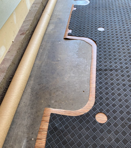 A black rubber mat on top of a piece of vinyl that's been cut about 2 inches larger.