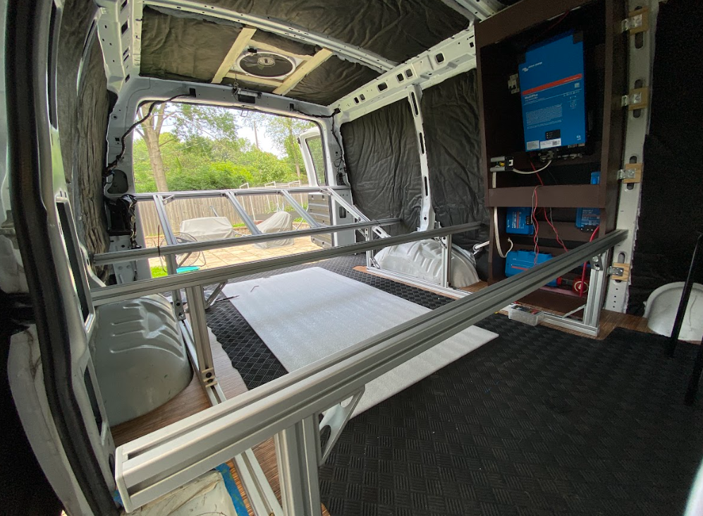 An aluminum bed frame inside a cargo van; view from the side door.