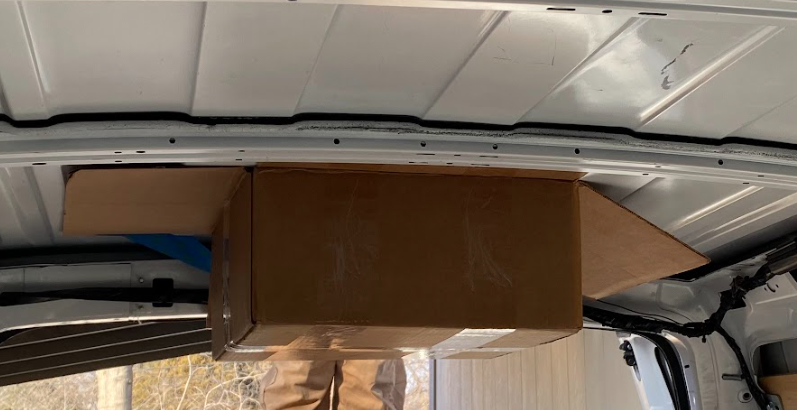 A cardboard box taped with the open top against the inside roof of the cargo van.