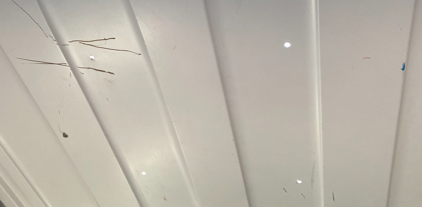 The white inside of a cargo van roof, with four holes arranged in a square.