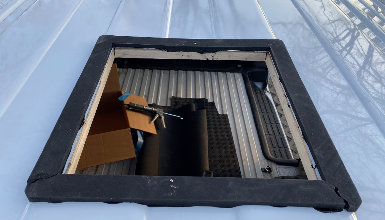 The cargo van hole from the outside, with the black square frame adhered around it.