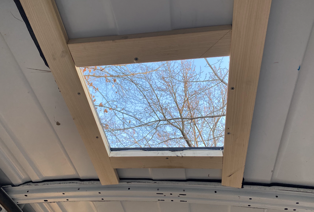 The cargo van hole from the inside, with a wood frame constructed around it.